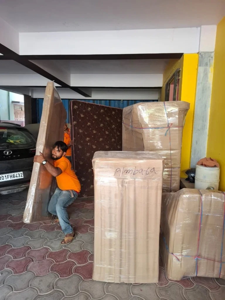 Worker from Mehar Packers and Movers handling packed furniture items at an IBA Approved Packers and Movers service center in Patna.